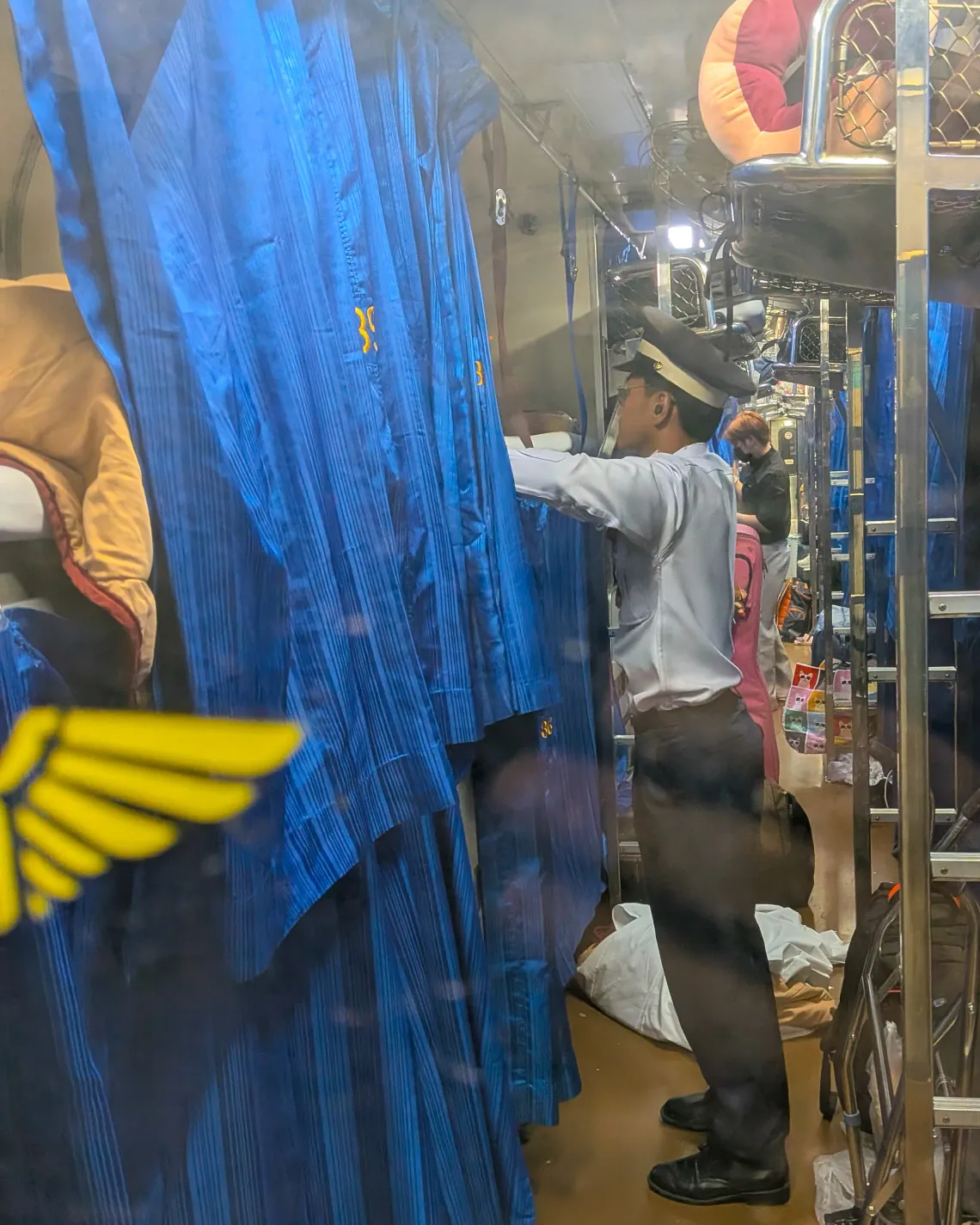 The Conductor on the Bangkok to Chang Mai line changes linens in anticipation of new passengers. 